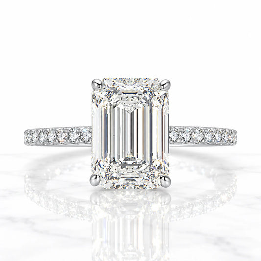 Silver statement ring with large emerald-cut center stone and pavé-set band on reflective white surface.