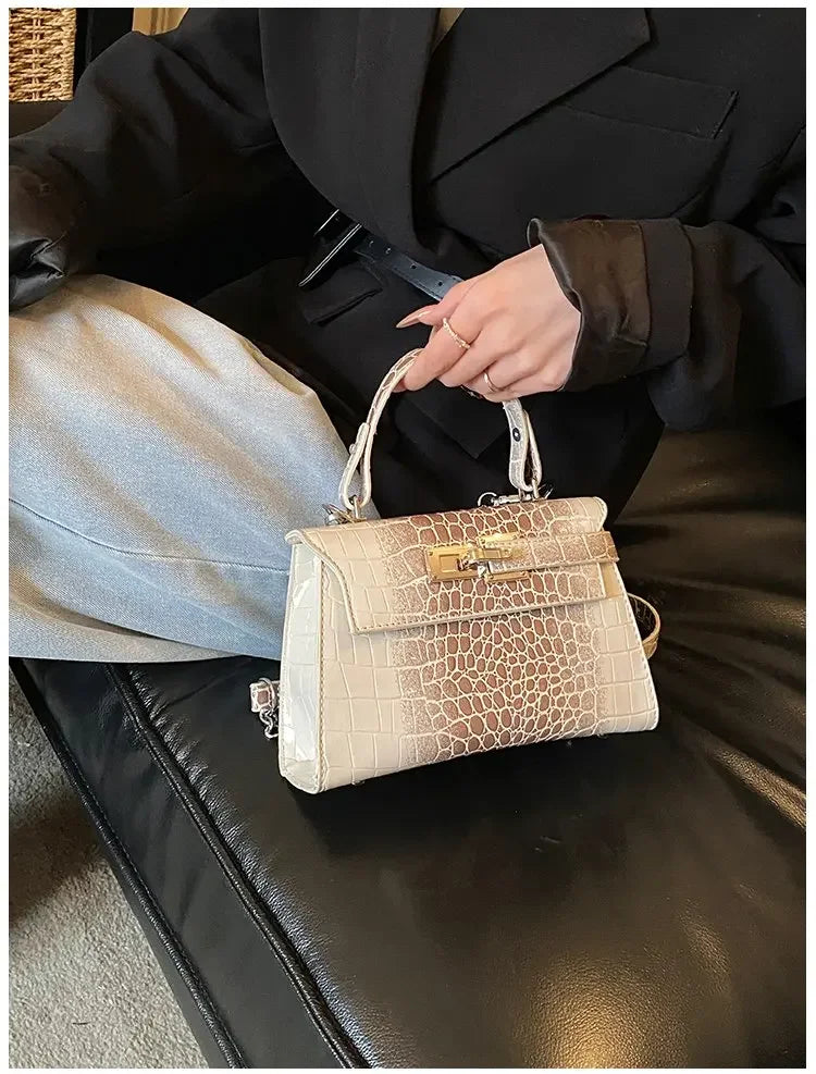 Beige faux leather structured diaper bag with crocodile texture and gold hardware for organized baby gear on the go.
