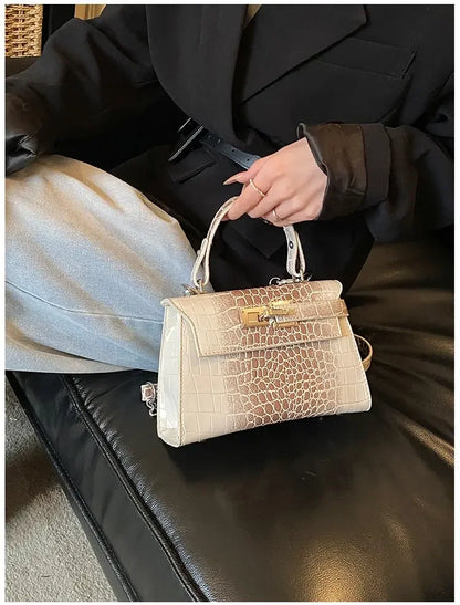 Beige faux leather structured diaper bag with crocodile texture and gold hardware for organized baby gear on the go.
