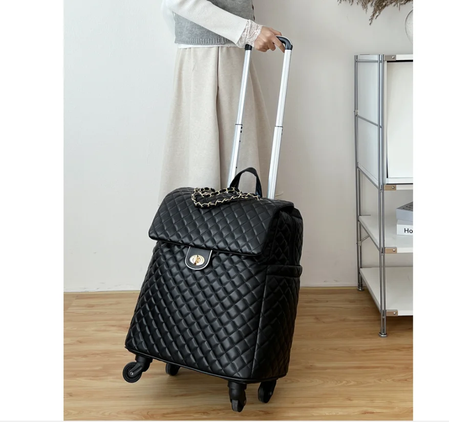 Black quilted faux leather travel suitcase with gold twist-lock closure, chain accent, and rolling wheels.