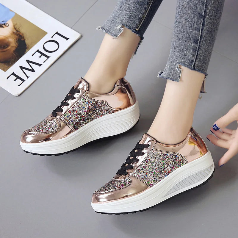 Rose gold metallic platform sneakers with sequin side panels, black laces, and thick white wedge soles.
