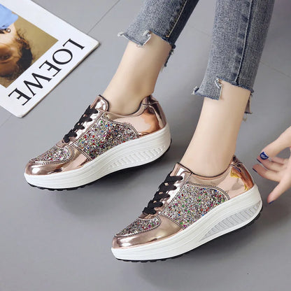 Rose gold metallic platform sneakers with sequin side panels, black laces, and thick white wedge soles.