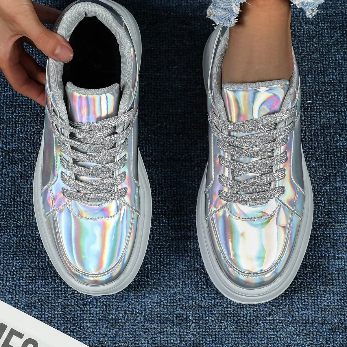Holographic silver casual sneakers with thick white soles and sparkly silver laces.