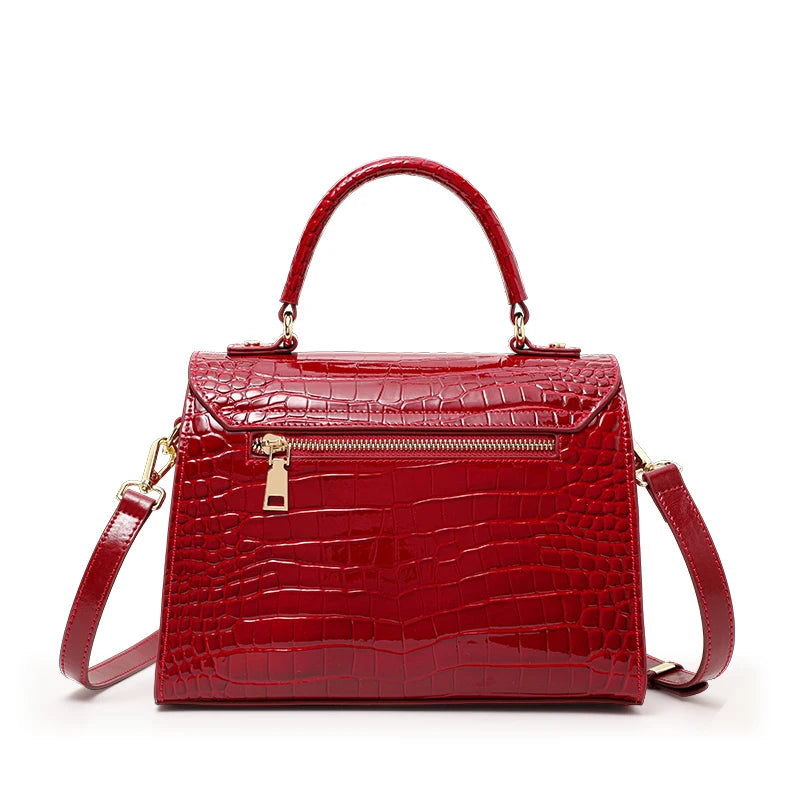 Red lacquer leather crocodile pattern handbag with gold hardware, top handle, and shoulder strap.