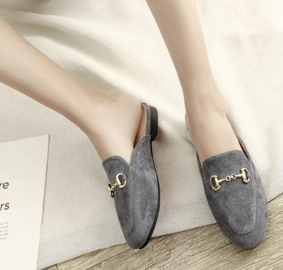 Grey suede slip-on mules with a gold metal chain detail, ideal for casual outdoor wear.