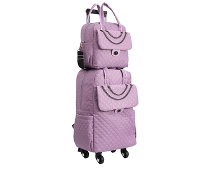 Light purple quilted rolling backpack and matching handbag set with chain accents and dual wheels.