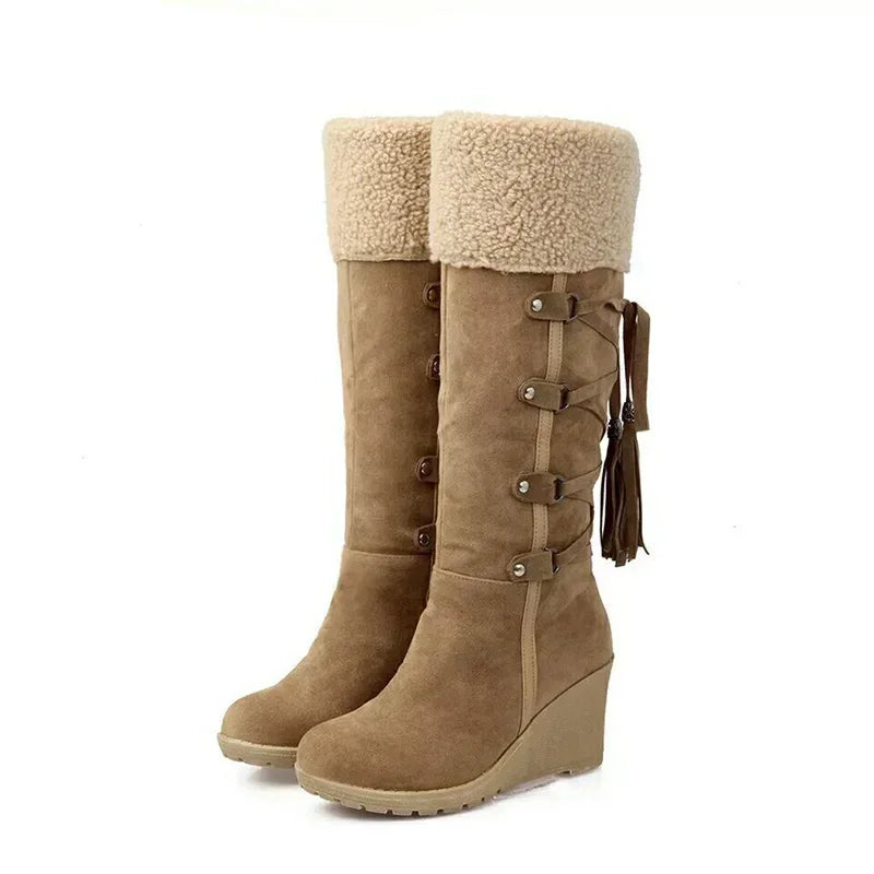Brown suede knee-high wedge snow boots with shearling cuffs and side tassels.