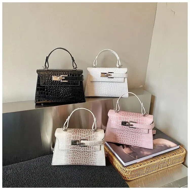 Black, white, and pink crocodile-textured faux leather diaper bag satchel with a structured design for baby supplies.