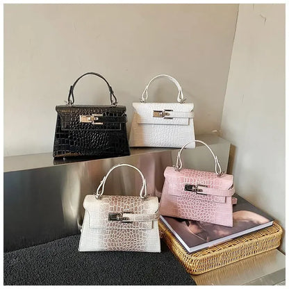 Black, white, and pink crocodile-textured faux leather diaper bag satchel with a structured design for baby supplies.