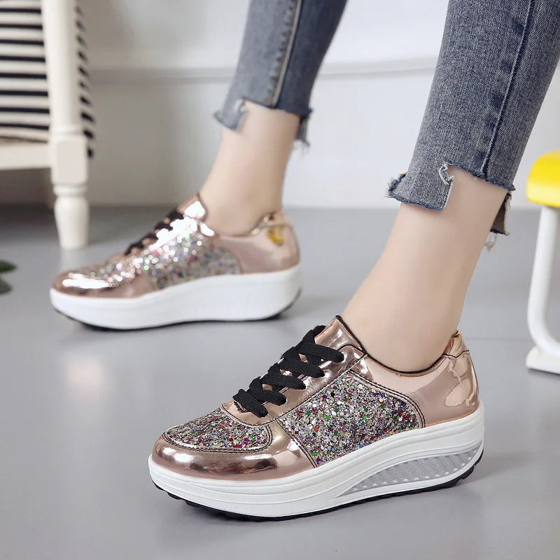 Rose gold metallic platform sneakers with sequined side panels, black laces, and thick white wedge soles.