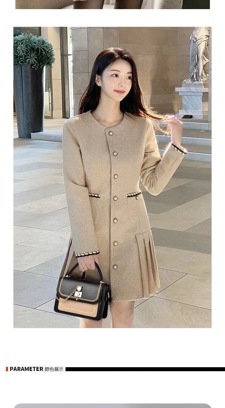 Black and tan leather handbag with top handle, clasp closure, and gold chain detail held by a woman.