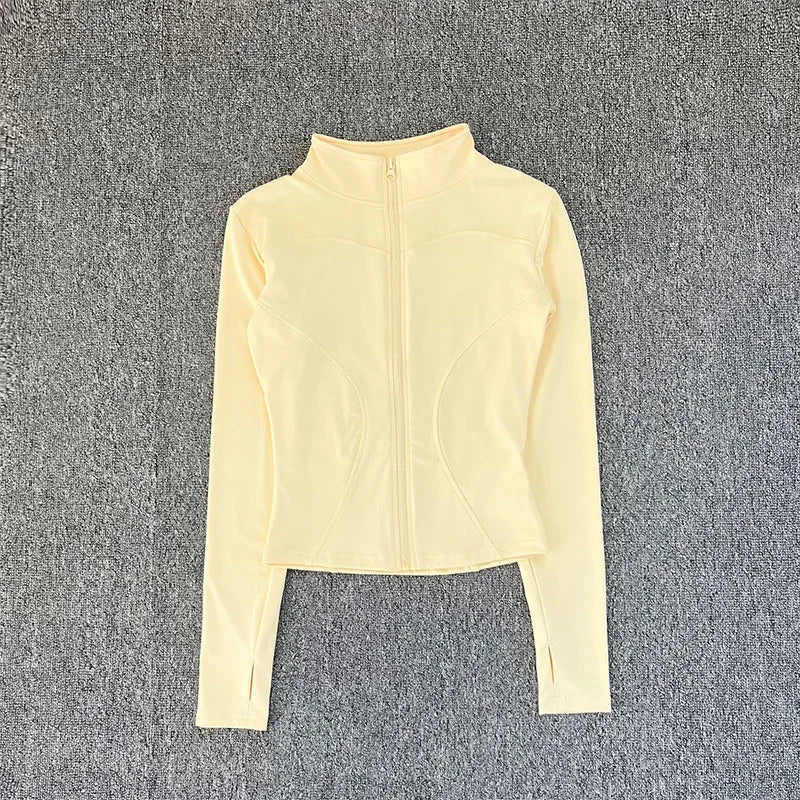 Pale yellow, fitted, zip-up polyester sport jacket with thumbholes for yoga training.