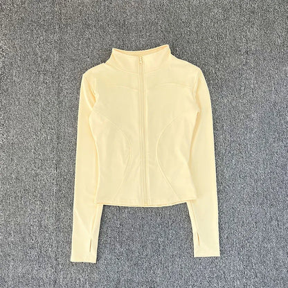 Pale yellow, fitted, zip-up polyester sport jacket with thumbholes for yoga training.