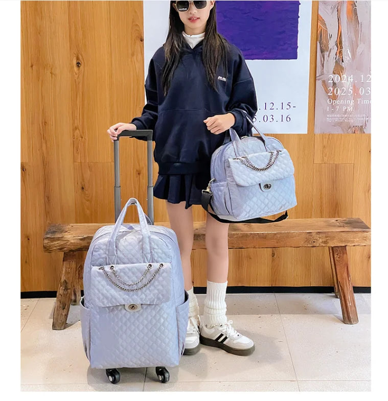 Light blue quilted rolling travel backpack with a front flap pocket, chain detail, and matching handbag.