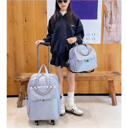Light blue quilted rolling travel backpack with a front flap pocket, chain detail, and matching handbag.
