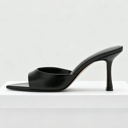 Black faux leather slip-on heels with an open toe design for formal party wear.