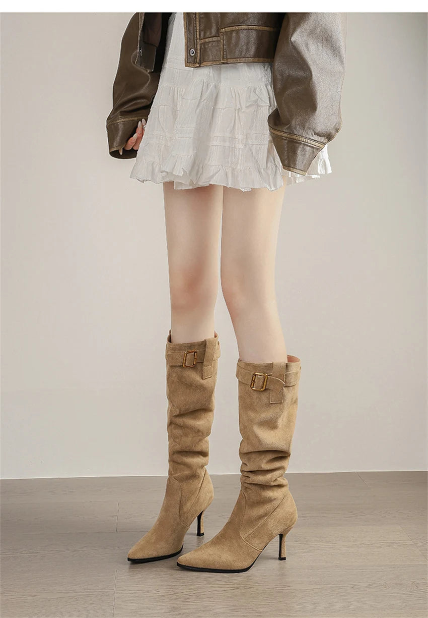 Tan suede knee-high slouchy boots with pointed toes, thin high heels, and buckled straps at the top.