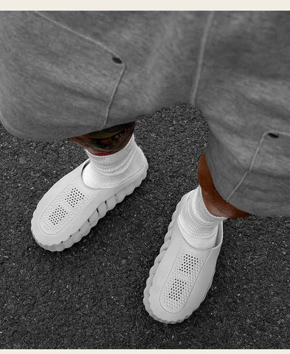 Light gray slip-on shoes with perforated design and cushioned platform soles for daily wear.