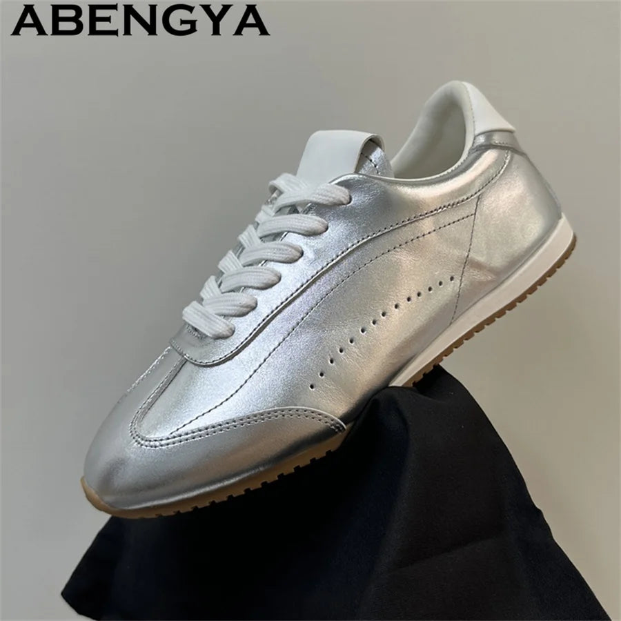 Metallic silver lace-up sneaker with white laces, white heel tab, and a brown ridged outsole.