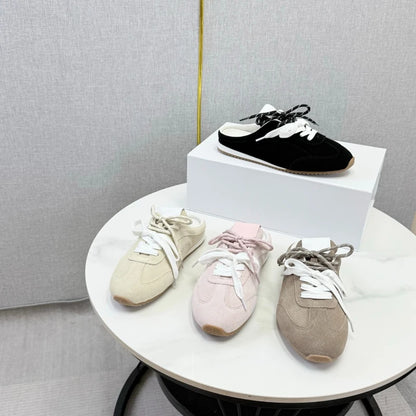 Four pairs of suede backless loafers in black, beige, pink, and brown, with round toes and white laces.