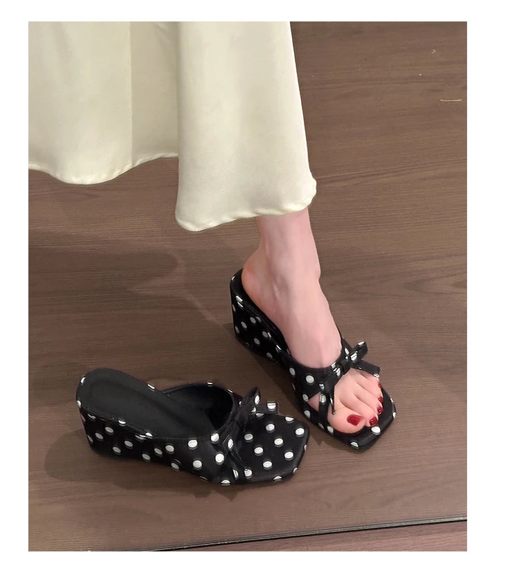 Black polka dot wedge sandals with a front bow and cushioned insole for casual wear.