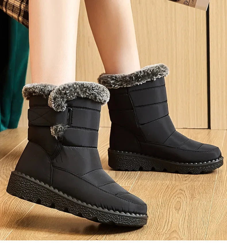 Black waterproof ankle snow boots with faux fur trim, side strap, and flat platform sole on person.