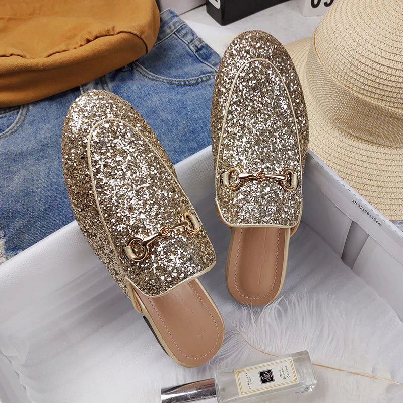 Gold glitter slip-on shoes featuring a metal chain detail for comfortable all-day wear.