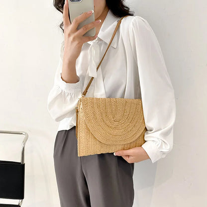 Tan straw envelope crossbody bag with an adjustable strap, ideal for summer beach outings.