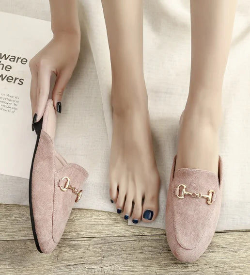 Pink suede closed toe slip-on mules featuring a gold metal chain for everyday outdoor wear.