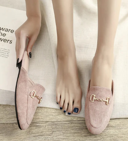 Pink suede closed toe slip-on mules featuring a gold metal chain for everyday outdoor wear.