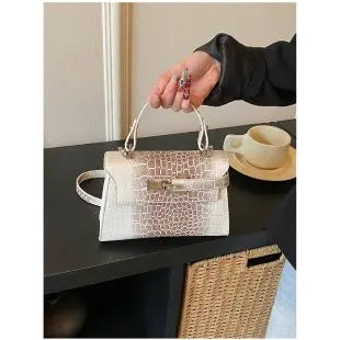 White faux leather structured diaper bag with crocodile texture, top handle, and adjustable strap for carrying baby gear.