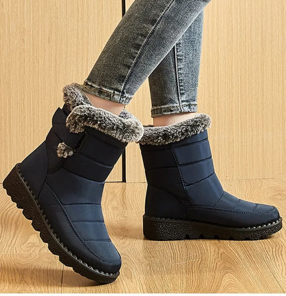Women's navy blue quilted winter snow boots with faux fur trim, side strap, and flat black rubber soles.
