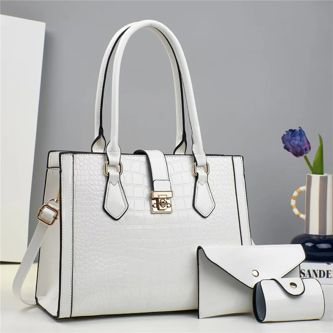 White crocodile-embossed faux leather tote bag with top handles, closure strap, and matching small wallet.