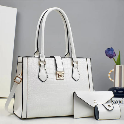 White crocodile-embossed faux leather tote bag with top handles, closure strap, and matching small wallet.