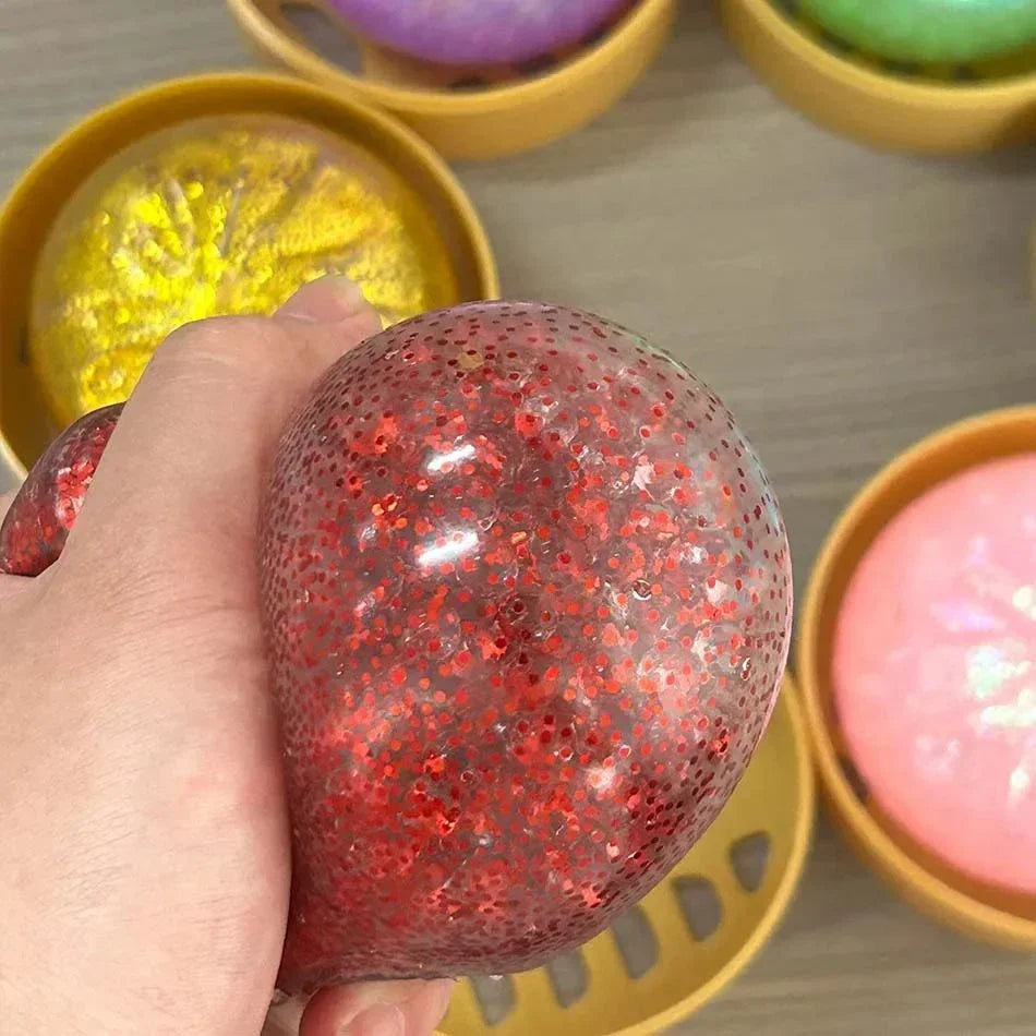 Clear red glittery dumpling squishy fidget toy in a yellow mini hot pot for sensory relief.