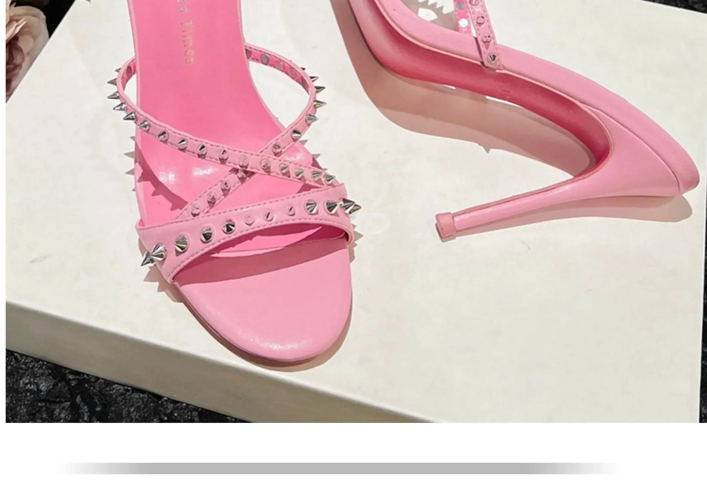 Pink open toe sandals with silver stud straps and slim heels for formal wear.