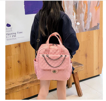 Pink quilted nylon backpack with a chain accent on the front pocket and top carrying handles.