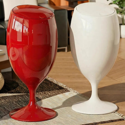Two wine-glass-shaped plastic trash cans in glossy red and white, standing on a rug.
