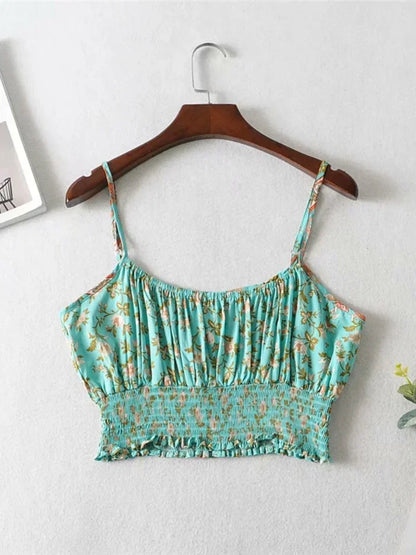 Teal floral flowy crop top with a gathered bodice and smocked waist, hanging on a wooden hanger for summer outings.