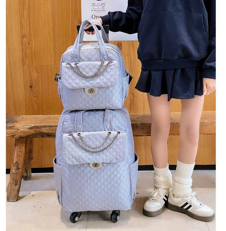 Light blue quilted rolling luggage set with chain accent, top handles, and front flap pocket.