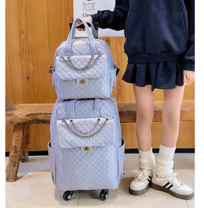 Light blue quilted rolling luggage set with chain accent, top handles, and front flap pocket.