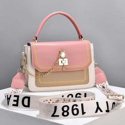 Pink, beige, and white faux leather handbag with gold hardware, a top handle, and a wide letter-printed strap.