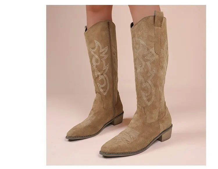 Tan suede western cowboy boots with pointed toes, block heels, and white contrast embroidery.