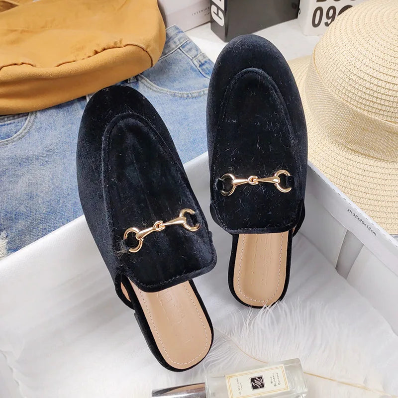 Black velvet slip-on shoes with gold chain detail, suitable for all day wear.