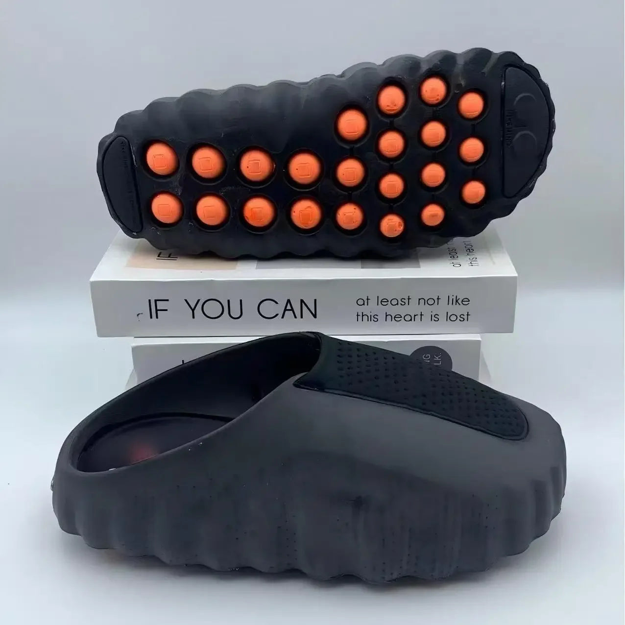 Black EVA sandals with orange massage nodules on the cushioned sole for daily walking.