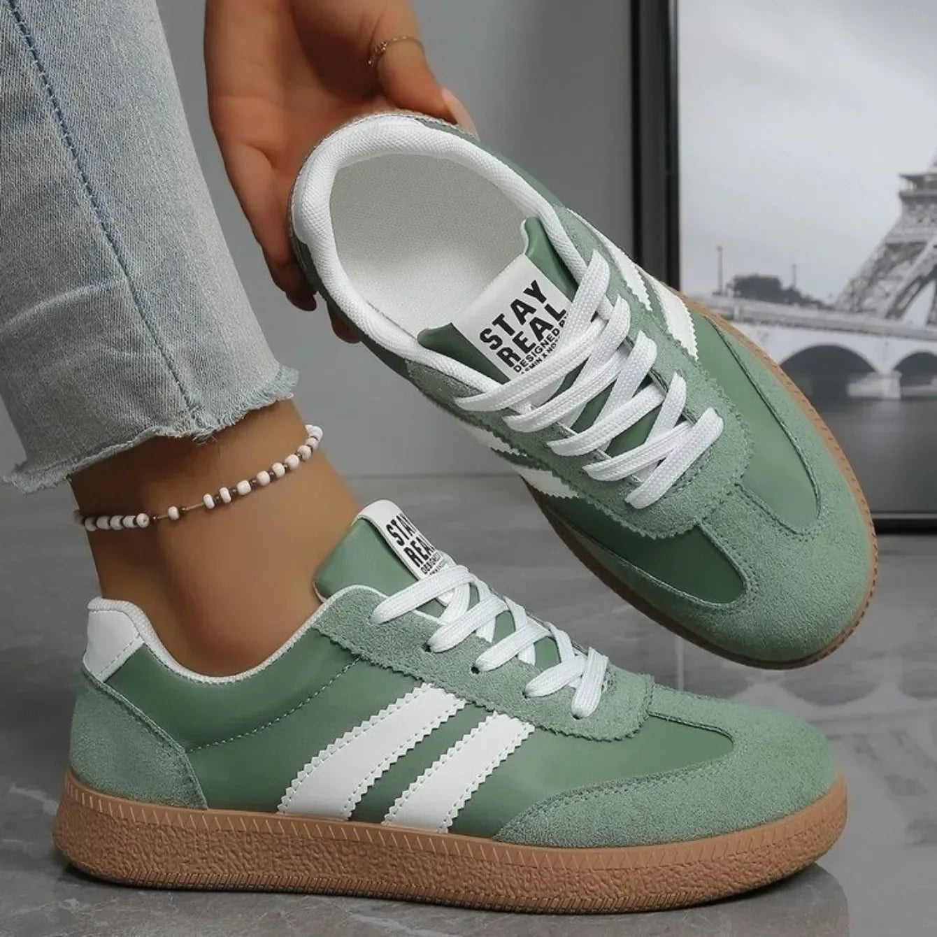 Sage green leather and suede slip-on sneakers with white stripes and gum soles for casual daily wear.