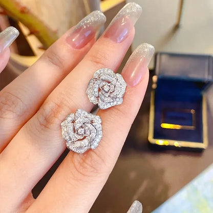 Silver-toned camellia flower stud earrings paved with sparkling clear cubic zirconia stones.