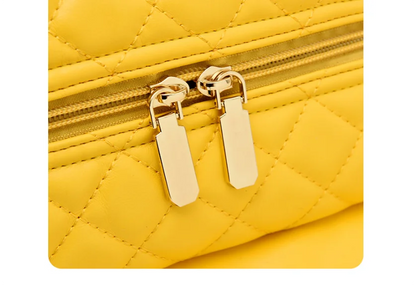 Yellow quilted material suitcase with gold zippers and metal zipper pulls.