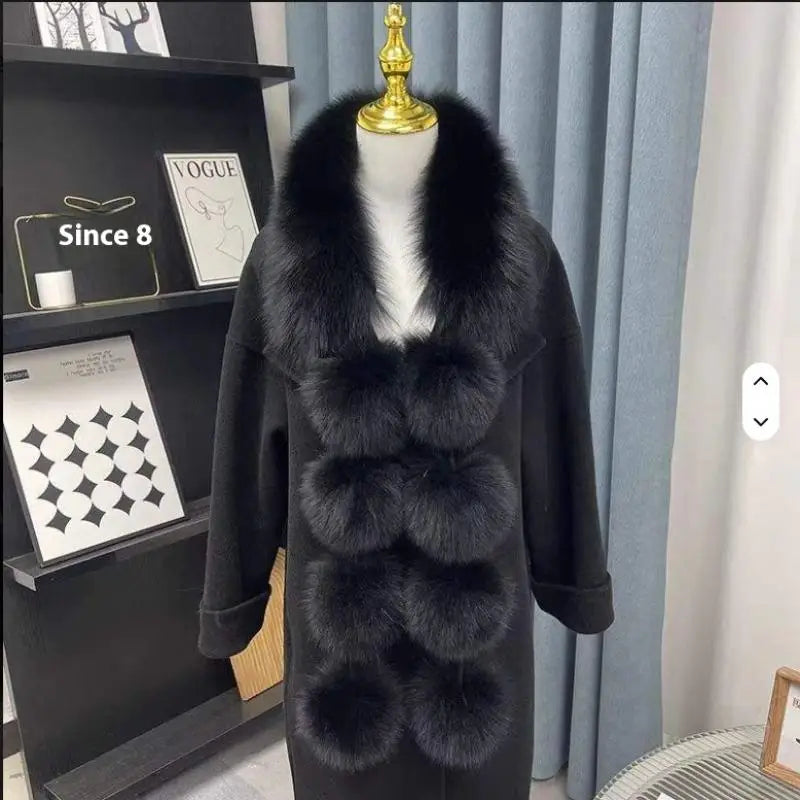 Black faux fox fur scarf with plush pom-poms on a black coat, worn on a mannequin.