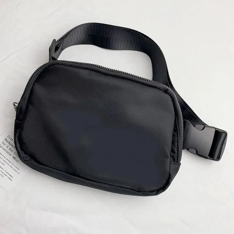 Black waterproof crossbody bag with zip closure and adjustable strap for running and yoga.